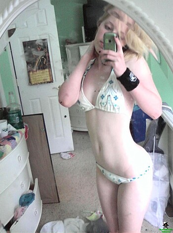 A busty blonde chick checking out her own hot bod in a mirror while wearing a skimpy bikini.