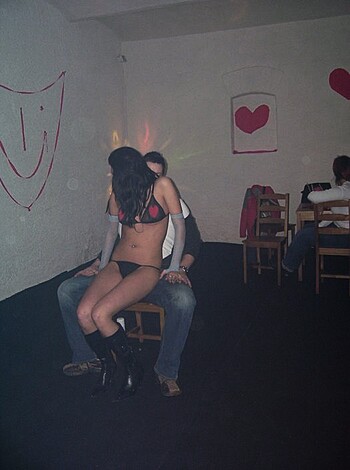 The fuck's going on here? A chick's got her tits out, and some dude's bussin' her lips while they sit on a dumbass chair inside.