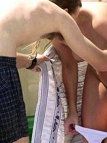 """
Guy's hand rubbing tits of chick at the shore, both without clothes.
"""
