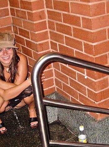 Brown-haired bitch with shitty shoes grins like an asshole, arms crossed over railings.