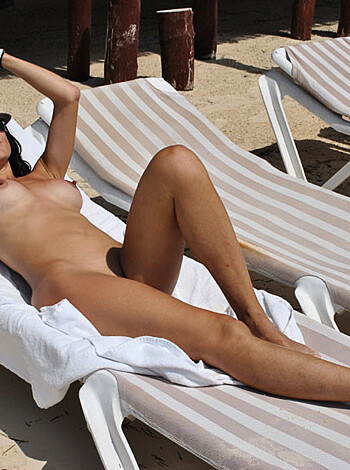 Vulgar Description: 
The photo shows a naked bitch in a beach chair, chillin' with some shades on her face while soaking up some rays.