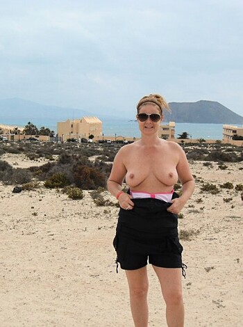 A naked chick standing with her tits out.