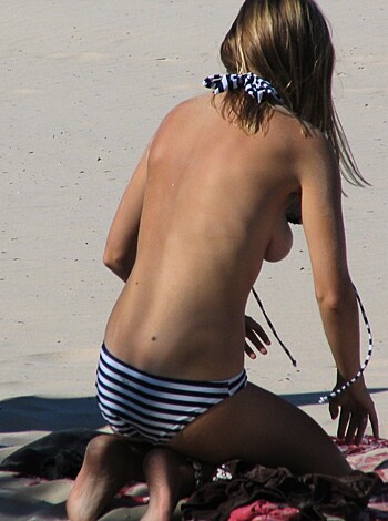 "Lady sitting on towel spread out, tits busting out her bra top."