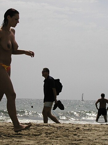 A bare-titted chick strolling down a packed fucking sandy shore surrounded by people with her jugs out for all to see.