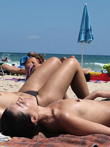 Three bikini-clad broads frolicking on the beach, tits out, asses out, flaunting their shit for all to see.
