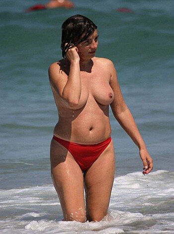 A fucking hot chick with a sexy body is walking on the sandy beach while dialing her cellphone and exposing her tits for all to see.