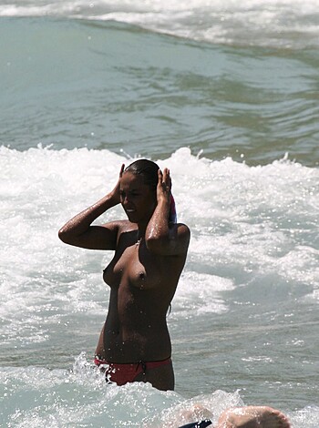 The naked broad with the juicy tits and tight ass in a red thong bikini hanging off her fat ass is standin' in the friggin' ocean, having some goddamn fun out there.