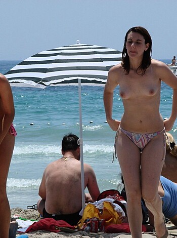 "Bare-boobed babes strolling on sandy shoreline."