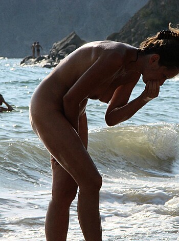 The fucking chick's taking a shit on the goddamn sandy shore, as others splash around naked ass-out in the fucking sea.