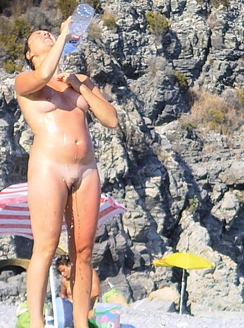 A topless, wet bitch on the shore, dousing her tits with some fucking bottled H2O.
