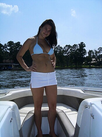 A hot chick in a skimpy bikini is posing next to a boat, showing off her toned legs in some tight ass white shorts.