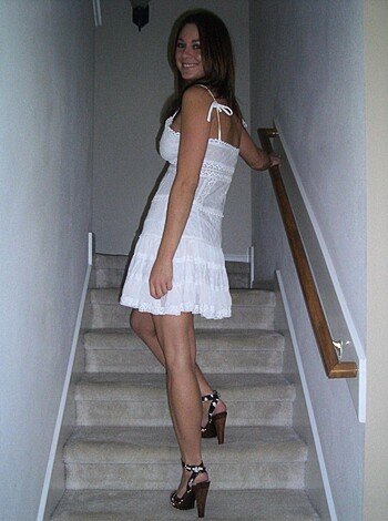 Look at this fucking hot bitch in her tight white dress with that see-through lacy shit, posing all seductive on those stairs like some kind of porno star!