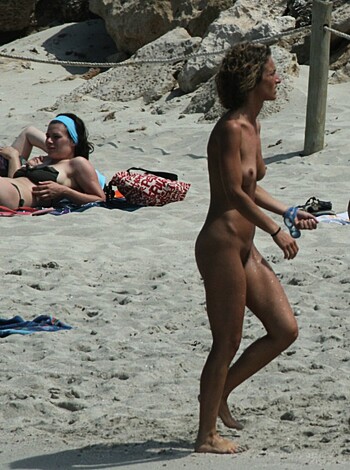 A bare-assed bitch on the sandy shore struts her stuff, her tits jiggling like jelly on a log.