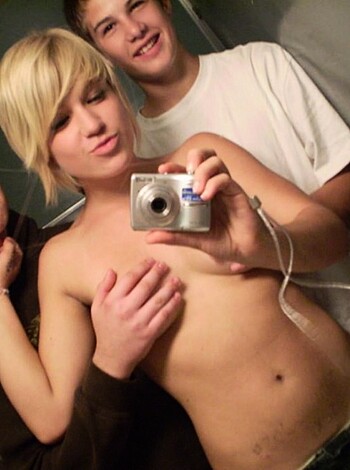 "Here's the image of a busty bitch posin' nude wit' her tits out in a john's mirror, whil' two dudes be makin' shitty faces behin' her."