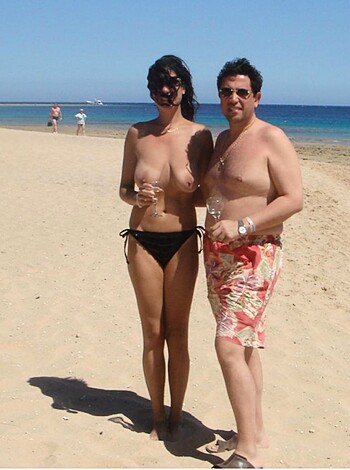 Dude and chick get naked on the sandy shore, basking in the sun's rays while feeling their bodies gently kiss by the warm waters of the sea.