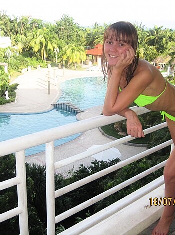 A hot, tanned chick in a fluorescent two-piece is grinding on the balcony rail while checking out the swimmin' hole below with its palm fronds swayin'.