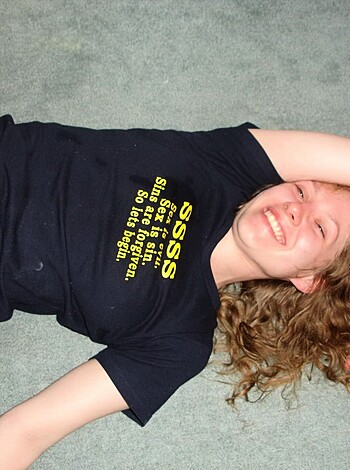 This image depicts a nude bitch lying down with a fucking grin on her face.