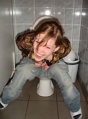 A broad chuckling bitch is comfortably seated upon a shitter.