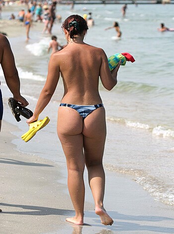 A scantily clad bitch sauntering along the sandy shore, her tits and pussy out for all to see.
