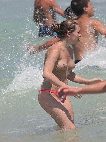 Naked broad on the shore, sportin' red thong knickers.