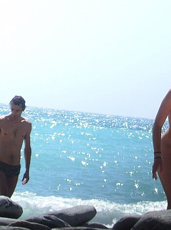 Three goddamn naked people stand on rocks overlooking the goddamn ocean, staring at each other's body parts.