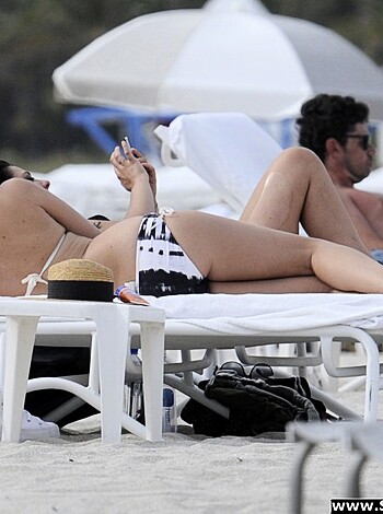 """
Two hot naked people chilling on a beach with some drinks and no shirts on.
""