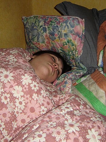 A naked b**** lying on her back with a blue sheet covering her face and snoring loudly.