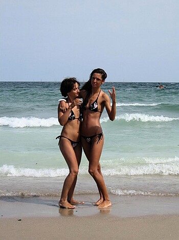 "Watch two chicks rubbing their asses on the sand while showing off their tits in bikinis."