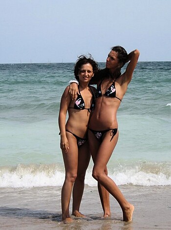 "Two hot chicks show their tits and asses at the beach."
