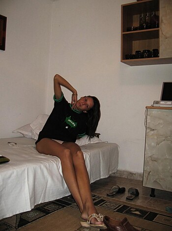 Vulgar description: "Look at this hot bitch sitting on her cozy bed, wearing a tight black tee and some skimpy shorts that barely cover her ass."