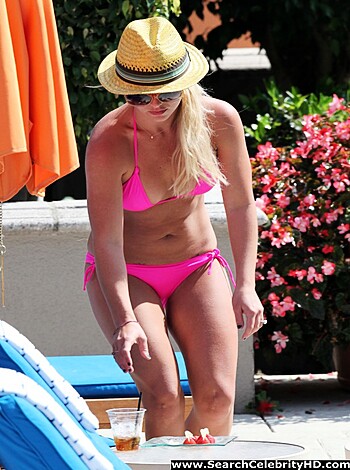 "Lusty lady sunbathing nude by the pool with her hot pink bikini bottom strategically placed on her hips."