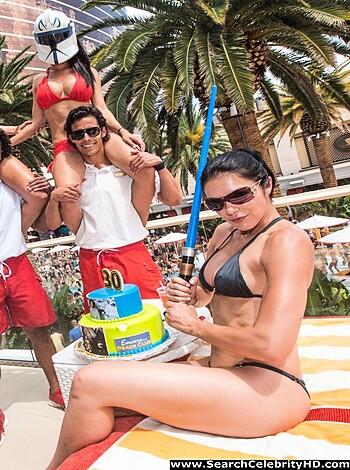 A busty babe with a blade, sporting a string bikini while flashing her pearly whites, poses for the camera.
