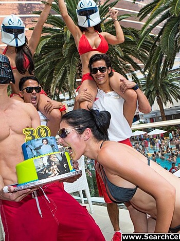 Here's a vulgar description of the image: 
This photo shows a bunch of fuckers getting wasted at a poolside rager. One dickhead's holding a birthday cake while some assholes are dressed in costumes. The scene looks like a goddamn good time.