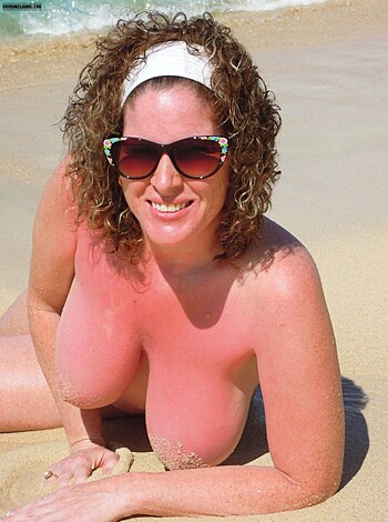 "Busty blonde babe sunbathing topless on a fucking hot beach with her juicy tits popping out of her bikini bottoms, sporting a pair of shades while giving you a cheeky grin. She's the definition of sexy and relaxed as she soaks up some rays."