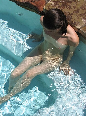 A naked bitch chilling in a swimming pool.