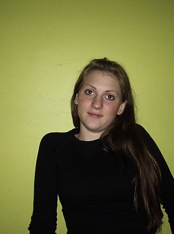 Here's a fuckin' picture of a hot bitch in a black t-shirt, rockin' her flowin' locks while posin' up against some dumbass yellow wall.