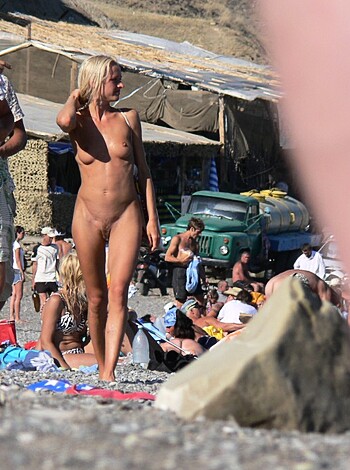 Busty bitch strollin' down the shore, sandy titties swingin', catching looks of dudes nearby.