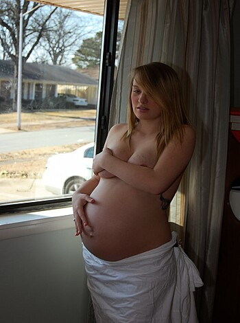 A nude knocked-up broad showing off her tits and belly, damn it!