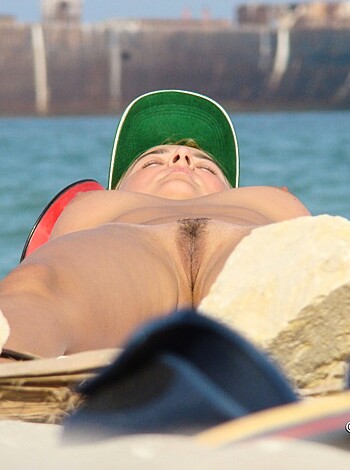 Fucking hot naked bitch laying down on sandy shore, her pussy and ass cheeks exposed to the sun while a guy with a camera tries to get in her shot without being detected by her man who's probably just around the corner.