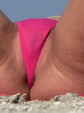 Here's a vulgar description of the photo: It's a fuckin' close-up of someone's ass in a pink thong, lying on some sandy beach shit.