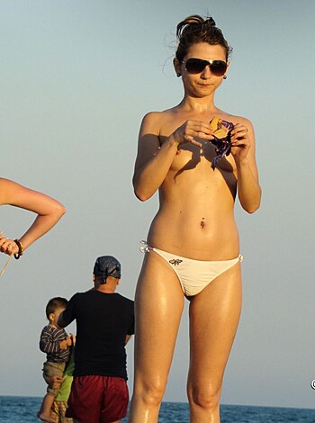 "Here's the fuckin' image you perverted bastard! It displays a fat, slutty broad sporting a tight white bikini bottom that barely covers her big ass cheeks and some tits. She's standing on a beach with a goddamn ocean in the background while another chick is almost visible behind her, also wearing a skimpy bikini top, probably enjoying her company as they both look like fucking sluts."