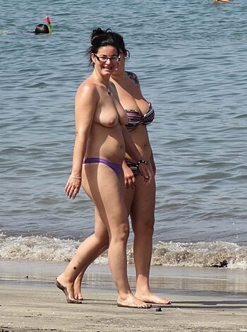 Strolling along the coastline, these two nude babes let their tits flop free.

 or

Heading down to the shore, these boobs-out bitches showed off their titties in the sand.