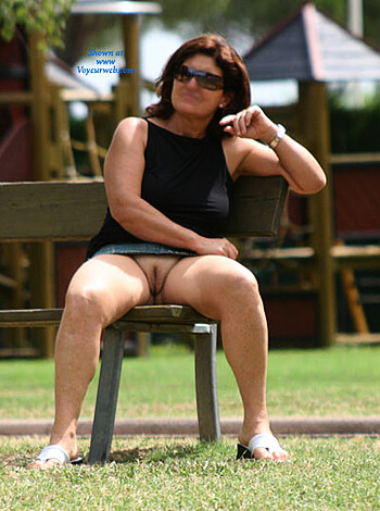 A broad-ass bitch in some tight ass clothes sits on a bench in the park with her fucking tits hanging out and shit while she rocks a pair of glasses and that's the only way to describe this motherfucking picture, dude.