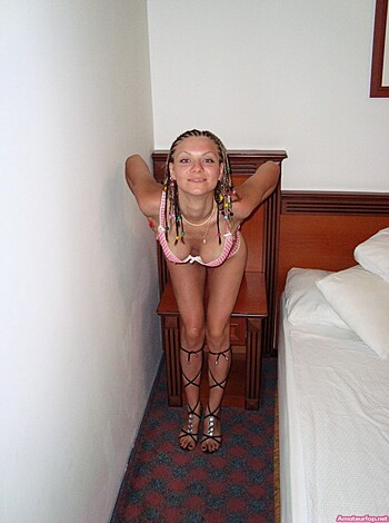 A hot chick in a bikini is posing on her bed with her legs spread wide open, showing off her sweet pussy while touching the sheets suggestively.