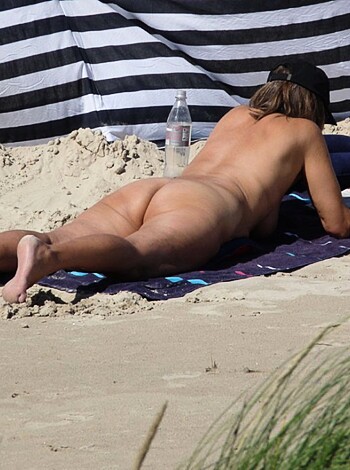 Here's a naked broad lying out on some sand with her tits and twat exposed for everyone to see.