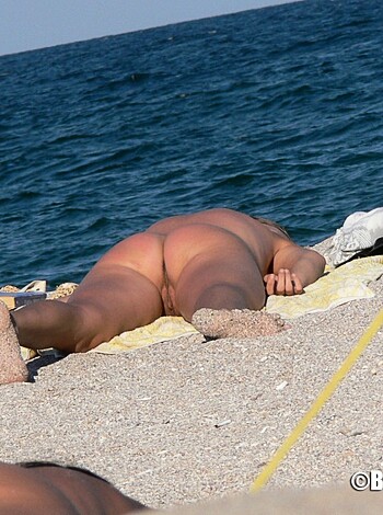 A chick, sans panties, tanning her booty on the sand.