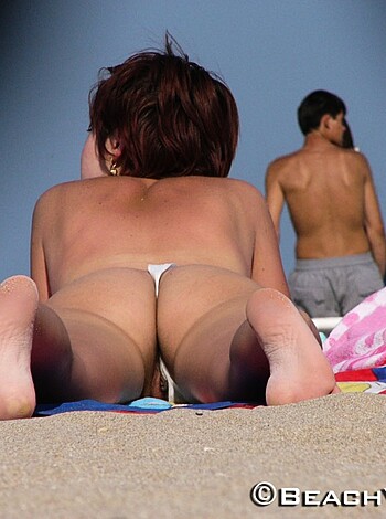 A naked female body lying on some sandy shore.