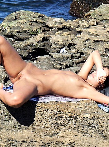A nude chick lies on her back with her tits out and her hand covering her pussy.