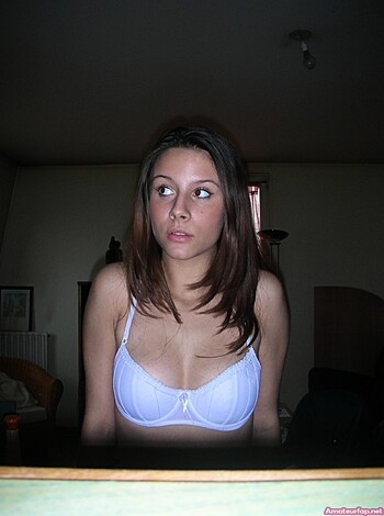 A chick in her undies checkin out the viewer with her tits hangin out of her bra and a smile on her face.