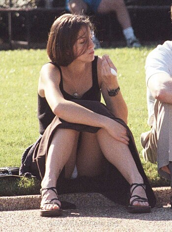 Here's the fuckin' image of some whore sittin' on a bench with a fag hanging from her lips, chattin' up some dude who ain't even in da shot.